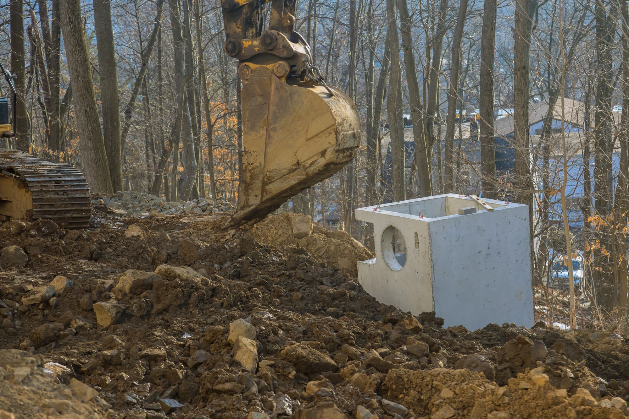 Excavator installing concrete tank
